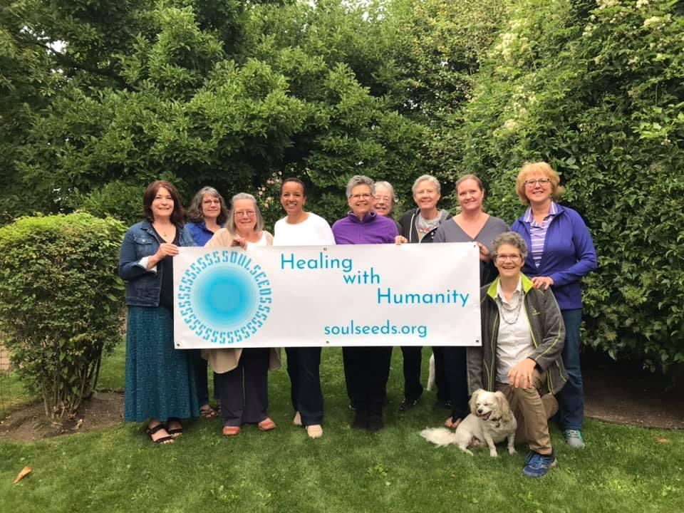 10 women holding a Healing with Humanity sign.